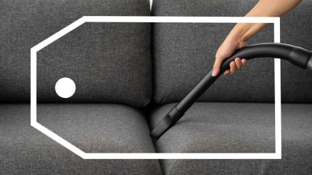 Person vacuuming a couch with a sales tag surrounding them
