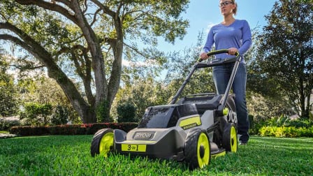 A woman pushing the Ryobi RY401170VNM on a lawn.