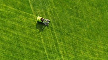 Overhead view of person on riding mower on an expansive lawn