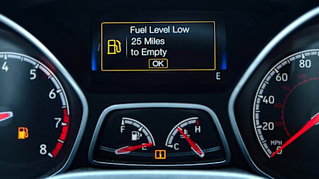 detail of car dashboard showing "Fuel Level Low, 25 Miles to Empty" on display