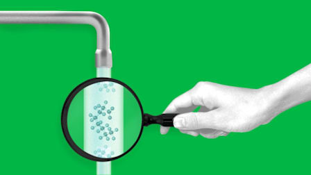 Hand holding magnifying glass looking through running water