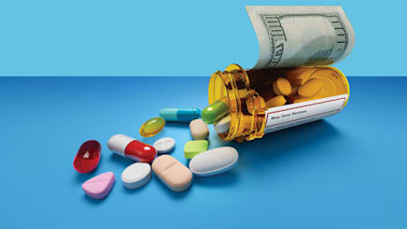 spilled prescription bottle with $100 bill as label and a variety of different pills coming out of the bottle