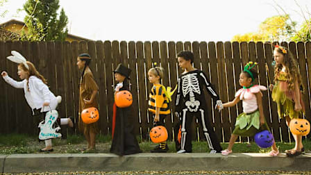 seven children dressed in halloween costumes walking in a line