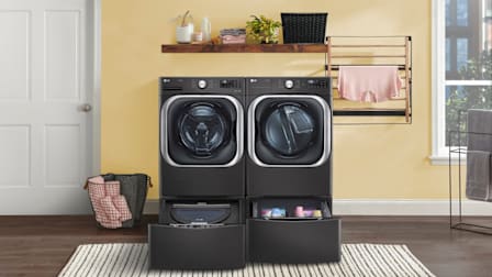 LG WM8900HBA washing machine and DLEX8900B/DLGX8901B dryer in room with yellow walls and white door