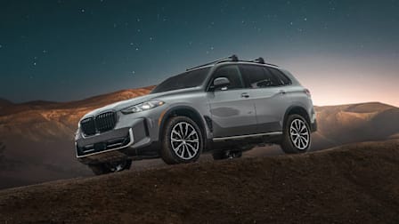 BMW X5 in silver with desert mountains and night sky in background