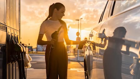 A woman at a gas station about to fill her vehicle with gas.