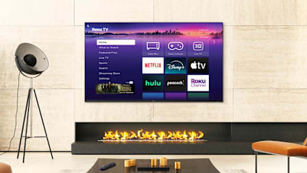 A Roku-branded TV in a living room setting displaying the home screen