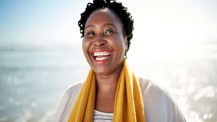 Dark skinned woman smiling at the beach.