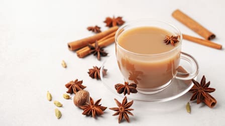 Chai in a glass cup with cardamom, star anise and cinnamon.