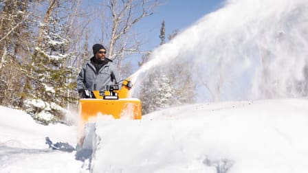 A person using a Cub Cadet 3X 26" TRAC snow blower to clear snow.