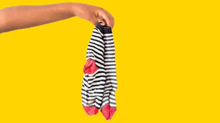 a pair of dirty socks handing from someone's hand