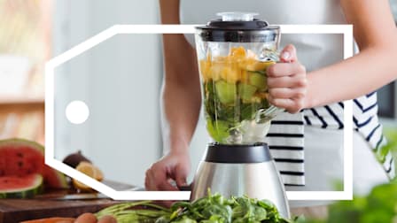Woman using blender for smoothie with vegetables and fruits.