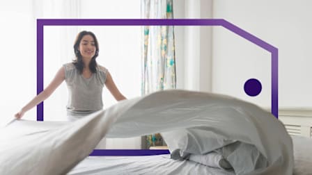 Woman making a bed, lifting a sheet in a bright, framed by a purple outlined price tag