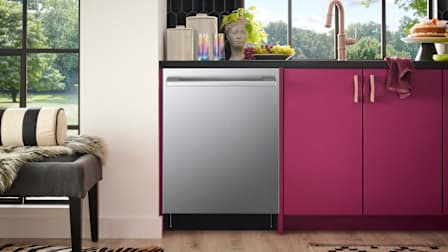 LG Studio SDWB24S3 dishwasher in kitchen with pink cabinets to right and ottoman with throw and pillow on left
