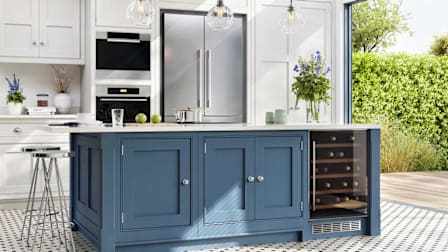 Modern kitchen with a blue island, built-in wine cooler, stainless steel appliances, and large windows overlooking a green garden.