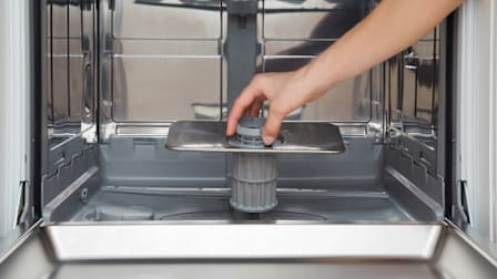 a hand removing a dishwasher filter