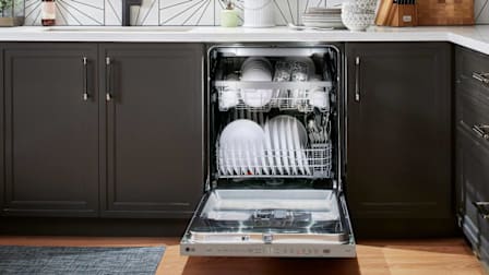 LG LDPH5554S dishwasher with door open showing white dishes and glasses, in kitchen with white countertop and dark grey cabinets