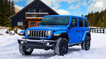 2025 Jeep Wrangler 4xe parked in the snow by a ski chalet