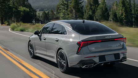 2025 Kia K5, seen from the rear driving down a road.