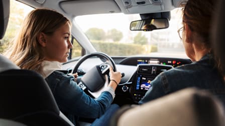 teenager behind wheel of car with parent sitting in passenger seat