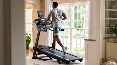 A man running on a Horizon 7.0 AT treadmill in a home.