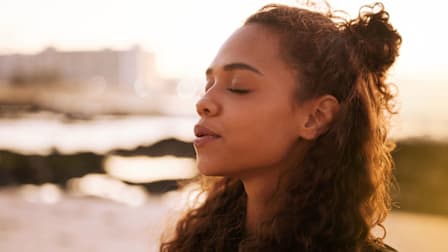 a woman breathing deeply with her eyes closed.