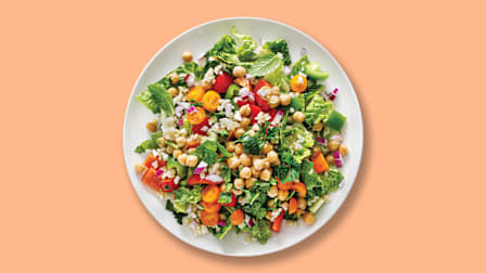 a salad with lettuce, tomatoes, peppers, onions, chick peas and herbs