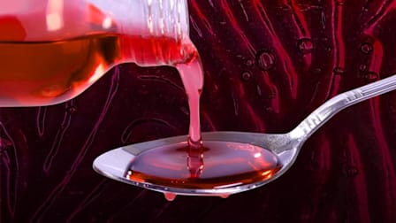 Red cough syrup pouring into a spoon