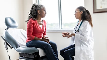 doctor talking to patient sitting on procedure chair while in doctor's office