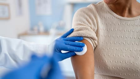 Doctor applying cotton round to the arm of a patient after vaccine.