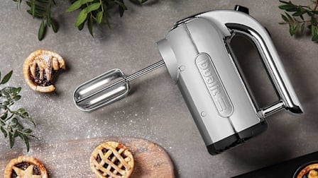 Dualit Professional 88520 4 Speed hand mixer on grey stone countertop with berry tartlets and wooden cutting board