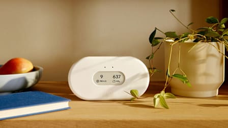 Airthings View Plus 2960 indoor air monitor on a shelf with household items.