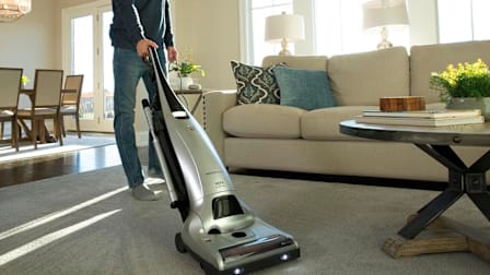 Person with a Kenmore vacuum on a rug in a living room