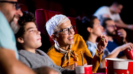 People clearly hearing a movie at a theater while eating popcorn
