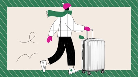 A person in winter clothes walking with a silver suitcase.