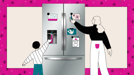 A woman and child decorating a refrigerator with holiday magnets.