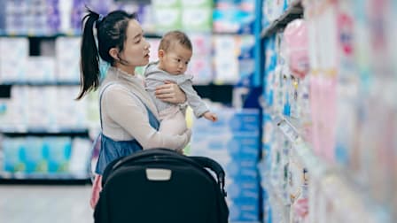 Mom holding baby in store looking at diapers