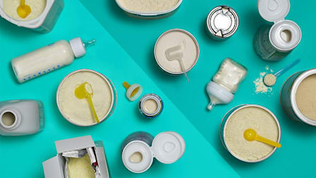 A number of liquid and powder baby formulas seen from above split between a lighter and darker shade of teal.