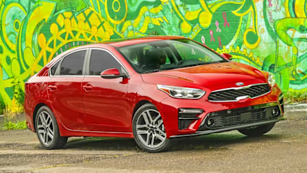 red 2021 Kia Forte on asphalt with green and yellow graffiti art in background