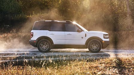 2026 Ford Bronco Sport seen driving on a dirt road in a forested environment.