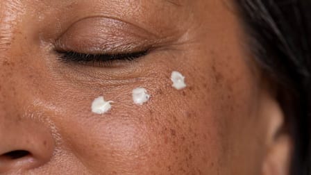 Closeup of a person's eye area with three dots of moisturizer under the eye.