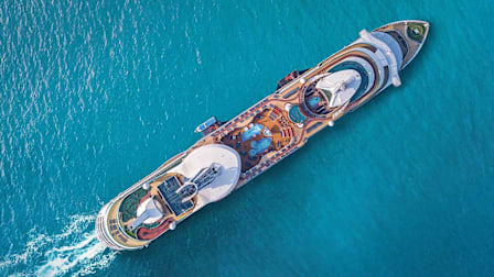 Aerial top-down view of a cruise ship, sailing on blue ocean water.