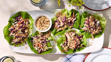 A white platter with five lettuce wraps filled with Crunchy Peanut Chicken Salad