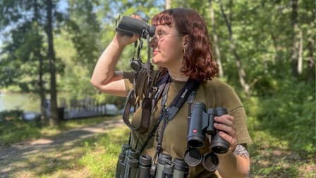 A tester using and wearing binoculars outdoors.
