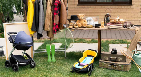 Clothes rack, old-fashioned suitcases, car seat, stroller, and misc items at garage sale