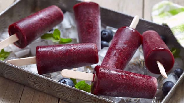 blueberry popsicles in metal tray with ice and blueberries