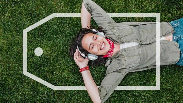 Person lying on the grass listening to headphones