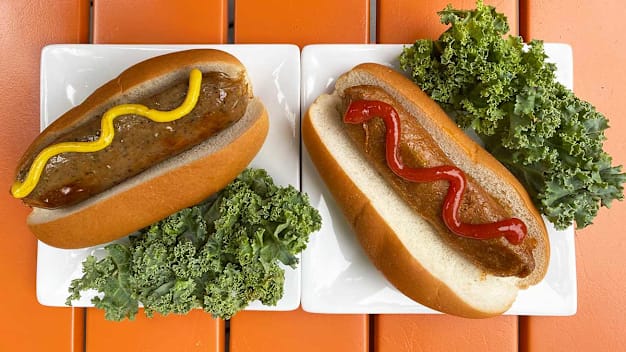 two hot dogs in buns on plates