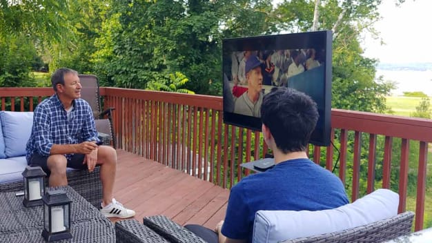 two people sitting on deck watching TV