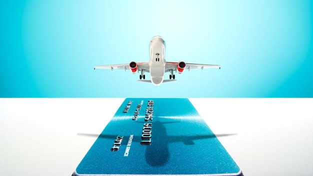 conceptual photo illustration of airplane flying above a credit card
